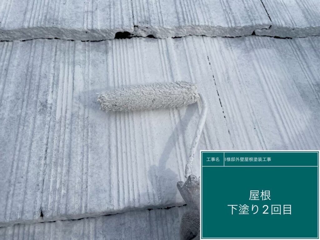 スレート屋根の下塗り2回目を行っています。劣化により塗料の吸い込みが激しかったため、1回目で終わらせずにもう一度下塗りを重ねます。屋根材自体の強度をしっかりと復元させ、仕上げ塗料が本来の耐久性を発揮できる土台を作ります。<br />
