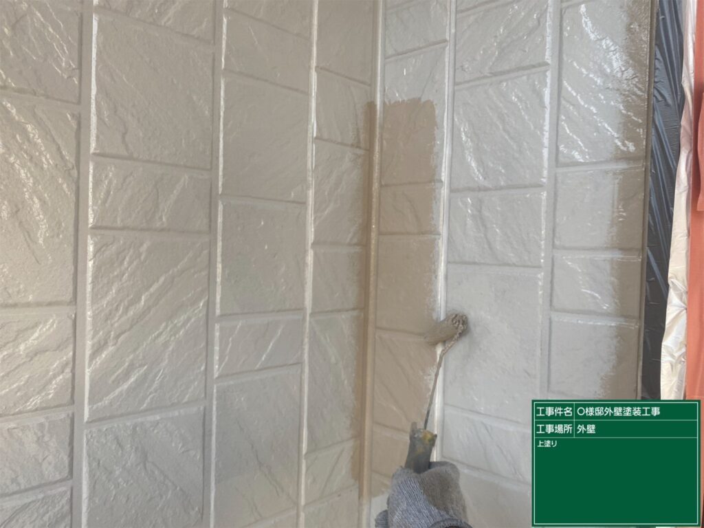 【外壁 上塗り施工中】<br />
外壁塗装の最終仕上げとなる上塗り（3回目の塗装）を行っています。塗料をもう一度重ねる「計3回塗り」を徹底することで、紫外線や雨風に何年も負けない最高強度の肉厚な塗膜を作り上げていきます。