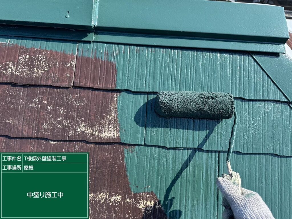 【屋根 スレート瓦中塗り施工中】<br />
下塗りが完全に乾燥した後、中塗り（2回目の塗装）を進めていきます。紫外線に強い高耐候性の遮熱塗料を使用し、屋根の重なり目や細かい部分までローラーと刷毛を使って色を均一にのせていきます。<br />
