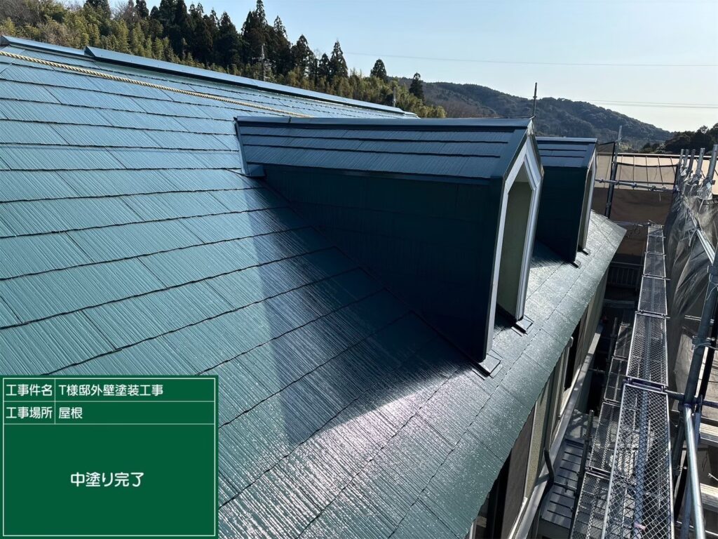 【屋根 スレート瓦中塗り施工後】<br />
屋根の中塗り工程が完了しました。スレート瓦全体が鮮やかに色づき、塗膜に十分な厚みが出てきましたが、ここからさらに仕上げの上塗りを重ねることで、ひび割れを防ぐ防水性と遮熱性をさらに確固たるものにしていきます。