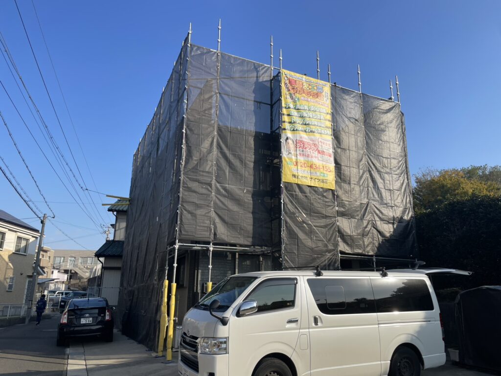 【足場設置・メッシュシート展開】<br />
職人が安全かつ精密な作業を行うための足場を組み立てました。近隣の皆様へ塗料や水が飛散するのを防ぐため、お家全体をしっかりとメッシュシートで囲い、配慮を徹底します。