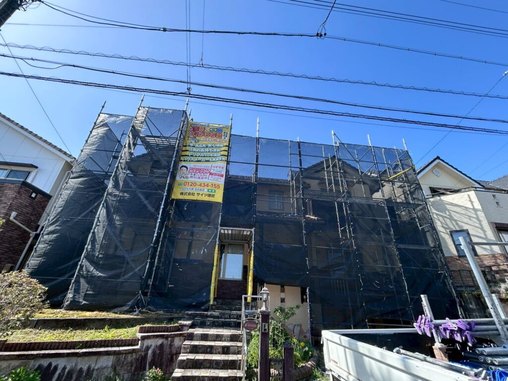【足場設置・メッシュシート展開】<br />
職人が安全かつ精密な作業を行うための足場を組み立てました。近隣の皆様へ塗料や水が飛散するのを防ぐため、お家全体をしっかりとメッシュシートで囲い、配慮を徹底します。<br />
