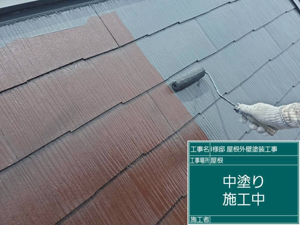 【屋根 スレート瓦中塗り施工中】<br />
下塗りが完全に乾燥した後、中塗り（2回目の塗装）を進めていきます。紫外線に強い高耐候性の遮熱塗料を使用し、屋根の重なり目や細かい部分までローラーと刷毛を使って色を均一にのせていきます。