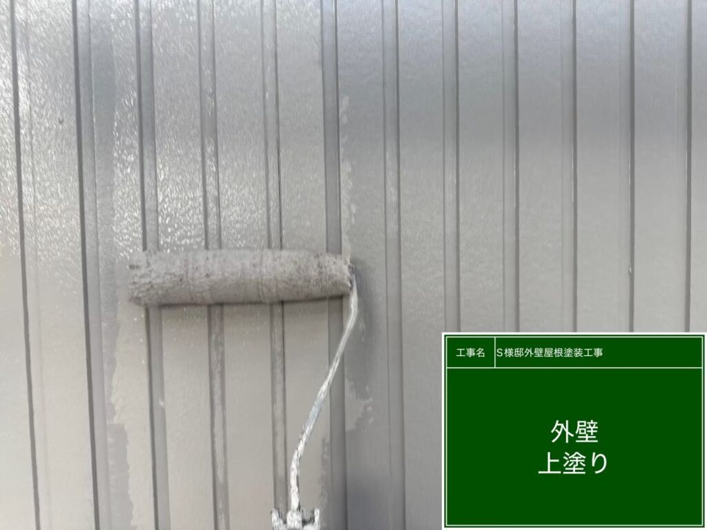 【外壁 ガルバリウム鋼板上塗り施工中】<br />
外壁リフォームの最終仕上げとなる上塗り（3回目の塗装）を行っています。中塗りと同じ高級塗料をもう一度重ねる「計3回塗り」を徹底し、メーカー規定の基準塗布量を完璧に守ることで、紫外線や過酷な太陽熱に何年も負けない強固な塗膜を形成します。