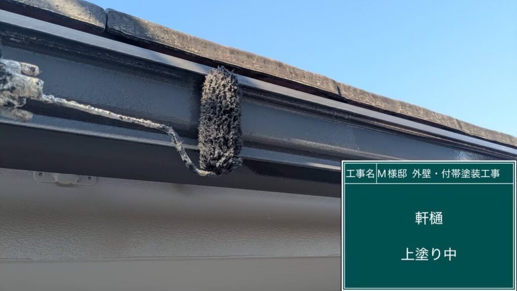 【軒樋 仕上げ2回目 施工中】<br />
フッ素塗料本来の耐久性と美観を極限まで引き出すため、仕上げの2回目を塗り重ねています。シリコン塗装を大きく超える長寿命な防水塗膜へと仕上げるため、ローラーの運行を均一にし、塗りムラや透けを一切残さない職人技で肉厚に仕上げていきます。<br />
