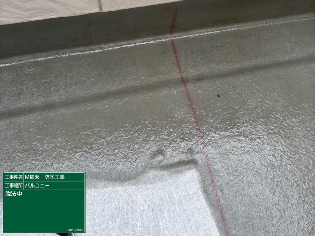 【FRP防水 脱泡（だっぽう）作業中】<br />
樹脂を染み込ませたガラスマットの中に空気（気泡）が残らないよう、専用の鉄製脱泡ローラーを使って限界まで気泡を押し出していく「脱泡（だっぽう）」工程です。ここに空気が残ると将来的に防水層が膨れたり割れたりする原因になるため、職人が目を光らせて徹底的に空気を抜いていきます。