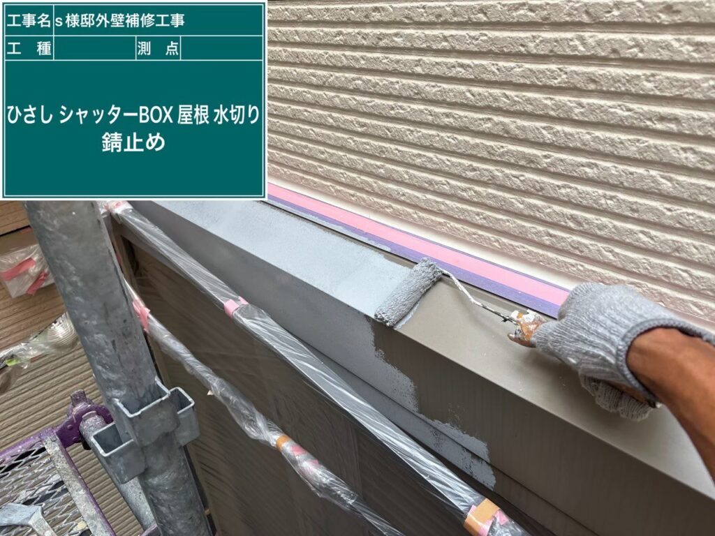 【シャッターボックス 錆止め塗布】<br />
ケレン後、すぐに強力な防錆（サビ止め）塗料を全体に塗布していきます。湿気や雨風が金属面に直接触れるのをブロックし、サビの発生を根本から防ぐための最重要下塗り工程です。