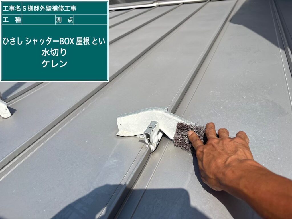 【屋根 瓦棒ケレン作業】<br />
瓦棒（金属屋根）の塗装前下地処理です。専用の工具やヤスリを使い、表面の軽微なサビや旧塗膜を落としながら、あえて細かな傷を付ける「目荒らし（ケレン）」を行います。このひと手間によって、新しく塗る錆止め塗料が金属面にガッチリと密着するようになります。<br />
